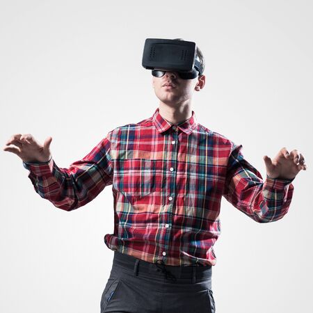 Young man in checked shirt wearing virtual helmet against gray backgroundの写真素材