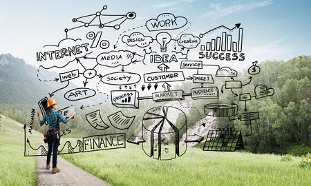 Back view of engineer woman in hardhat outdoor and sketched concept on screenの写真素材