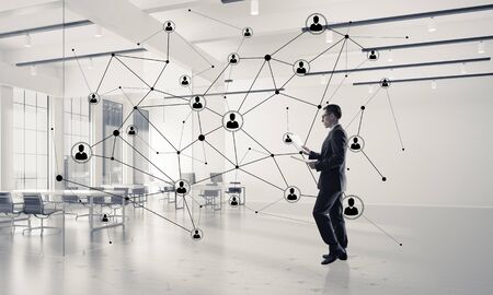 Elegant businessman in 3D office interior and social connection concept. Mixed mediaの写真素材