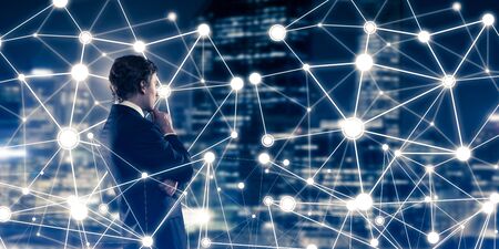 Businessman against night cityscape looking at social connection media conceptの写真素材