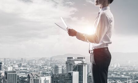 Young elegant businessman with papers in hands looking awayの写真素材