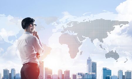 Young elegant businessman with hand on chin looking awayの写真素材