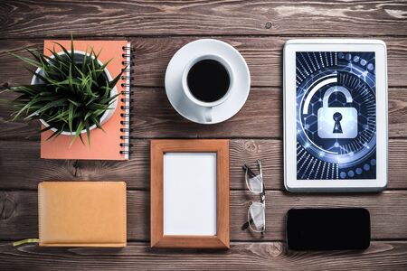 Business workplace with office stuff and tablet with padlock icons on screenの写真素材