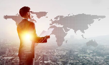 Double exposure of elegant businessman with papers in hands looking awayの写真素材