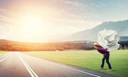 Builder man carrying paper ball on his backの写真素材