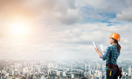 Engineer woman with blueprint on modern city landscape