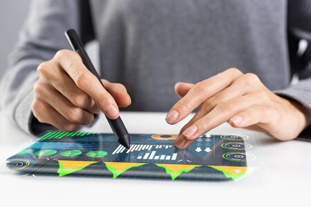 Woman using digital tablet computer at office desk. Close-up of female hand holding pen and touching...