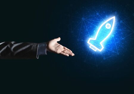 Rocket glowing icon and businessman hand on dark backgroundの写真素材