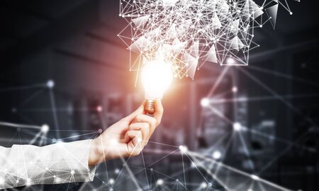 Human hand with glowing lamp and abstract digital network on dark office background. Professional...