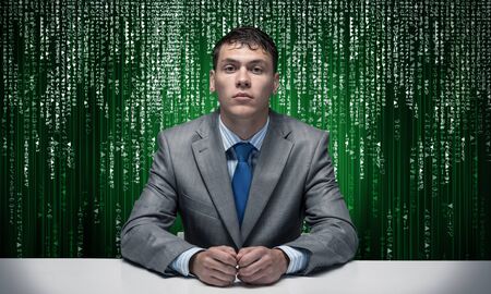 Handsome serious man with folded hands on binary computer code background. Online safety consultant...