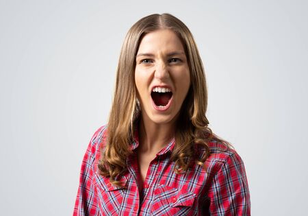 Frenzied young woman screaming with anger. Emotional girl has furious facial expression. Portrait of...