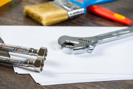 Water braided metal hose with connecting internal screw. Close up flexible hydraulic system. Plumbing pipeline laying on office table. Water hosepipe planning and installation project.の写真素材