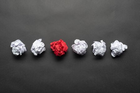 Crumpled red paper ball among white balls on black background. Extraordinary solution of problem. Business motivation with copy space. Unique and different experience. Idea generation and imaginationの写真素材