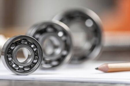 Three various ball bearings lying on paper sheet. Heavy industry engineering company. Automotive...