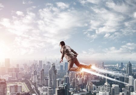 Businessman in suit and aviator hat flying in blue sky as superhero.  New challenges and winning....