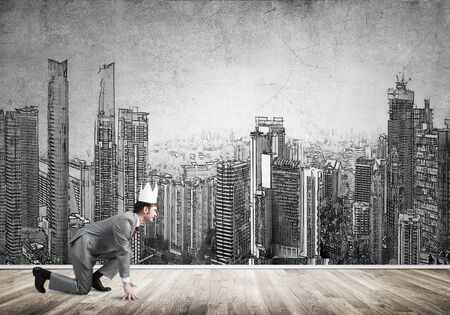 Young handsome businessman wearing white paper crown running in a hurryの写真素材