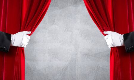 Close up of two hands in white glove open red velvet curtainの写真素材
