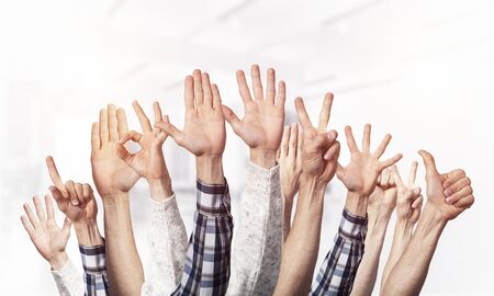 Row of man hands showing various gestures. Ok, finger pointing, victory, spread fingers, clenched fist and thumb up signs. Human hands gesturing on light blurred background. Many arms raised together.の写真素材