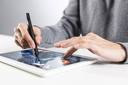 Close-up of female hands touching screen of digital tablet. Businesswoman sitting at desk and...