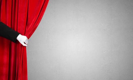 Close up of hand in white glove open red velvet curtainの写真素材