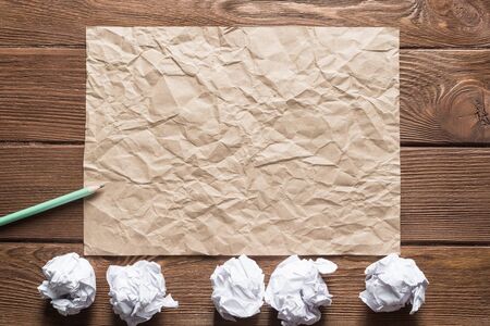 Crumpled brown paper sheet and pencil on wooden tableの写真素材