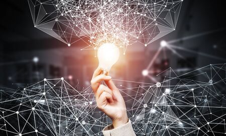 Human hand with lamp and abstract network composition on dark office background. Science research and innovation. Internet marketing and business development. Mixed media with virtual networkの写真素材