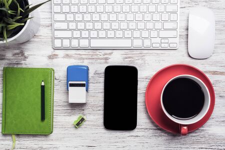 Top view businessman workplace with office accessories. Morning coffee time and planning new day. Flat lay wooden desk with computer keyboard and mouse, diary, smartphone and rubber stamp.の写真素材