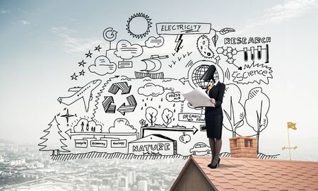 Faceless businesswoman with camera zoom instead of head standing on house roofの写真素材