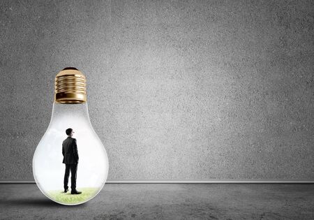 Businessman inside of light bulb in empty concrete roomの写真素材