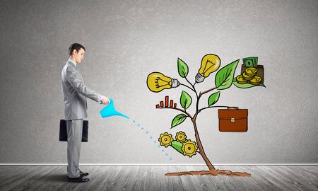 Businessman watering drawing tree with can. Green plant consisted of business infographic signs. New startup development. Business support and assistance metaphor. Investing into ideas.の写真素材