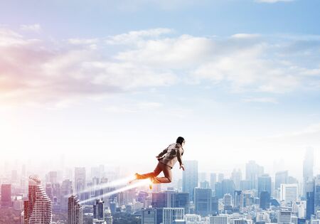 Businessman in suit and aviator hat flying in blue sky as superhero. Business person as launching...