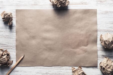 Crumpled brown paper sheet and pencil on wooden tableの写真素材