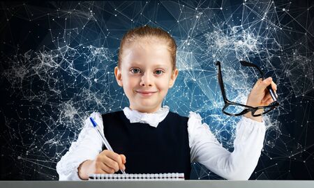 Smiling little girl in schoolwear doing her homework. Time to study concept. Happy schoolgirl with...