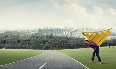 Young man builder carrying growing graph on his backの写真素材