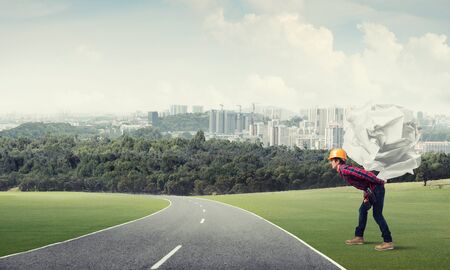 Builder man carrying paper ball on his backの写真素材