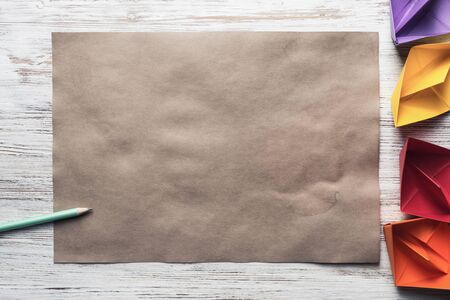 Crumpled brown paper sheet and pencil on wooden tableの写真素材