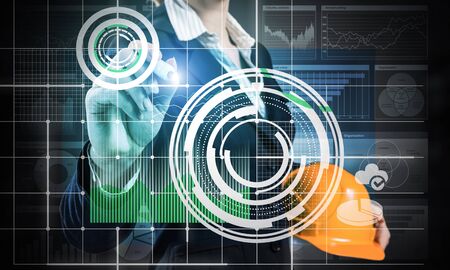 Businesswoman pointing on 3d financial graph. Woman in business suit standing with safety helmet....