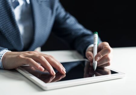 Man in business suit using tablet computer. Close-up of male hands holding pen and tablet gadget. Businessman at workplace in office. Business occupation and mobility, internet smart technology in jobの写真素材