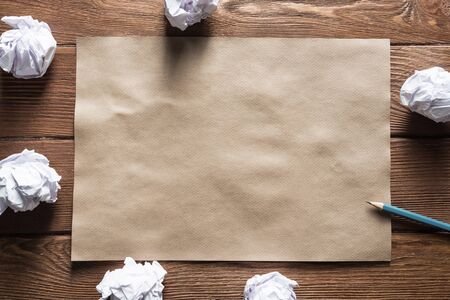 Crumpled brown paper sheet and pencil on wooden table
