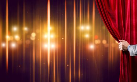 Close up of businessman hand open red velvet curtain of stageの写真素材