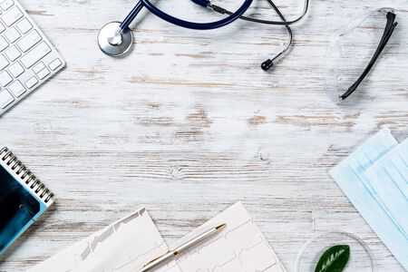 Doctors desktop with medical supplies. Computer keyboard, x-ray image, stethoscope and cardiogram lies on wooden desk. Healthcare technology concept with copy space. Medical consultation and treatmentの写真素材