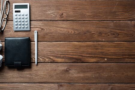 Still life of accountant workspace with office accessories. Flat lay vintage wooden desk with black...