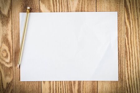 Minimal wooden desk workplace with blank paper. White a4 format paper with pencil. Textured natural...