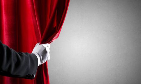 Close up of hand in white glove open red velvet curtainの写真素材