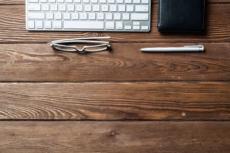 Still life of office workspace with supplies. Flat lay old hardwood desk with black leather wallet and computer keyboard. Online shopping and payment. Creativity and innovation concept with copy spaceの写真素材