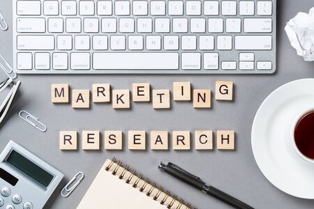 Marketing research concept with letters on cubes. Still life of office workspace with supplies. Flat lay grey surface with pc keyboard and calculator. New strategy planning and workflow optimization.の写真素材