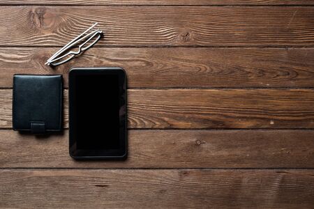 Still life of office workspace with supplies. Flat lay old hardwood desk with black leather wallet...