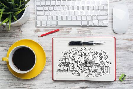 Flat lay wooden desk with computer keyboard, mouse and cup of coffee. Open diary with financial diagrams doodles. Top view modern office workplace. Business analytics and strategy planning.の写真素材