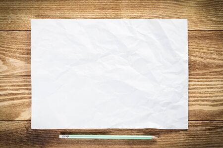 Minimal wooden desk workplace with blank paper. White a4 format paper with pencil. Textured natural wooden background. Vintage copy space for creative design and advertising. Business planningの写真素材