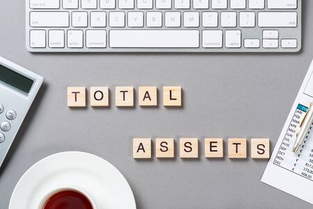 Total assets concept with letters on wooden cubes. Still life of office workplace with supplies....